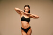 © GVS - Sensual slim woman in black underwear posing on beige studio background