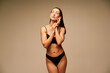 © GVS - Sensual slim woman in black underwear posing on beige studio background