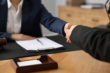 Canvas Print - Notary shaking hands with client at wooden table in office, closeup