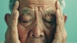 An elderly man with closed eyes holding his temples in his hands conveying a sense of deep thought or concern.