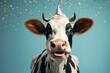 happy cow in a festive hat under falling confetti on a blue background. funny animal concept