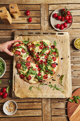 Wall Mural - Freshly baked delicious pizza with tomato-mozzarella and arugula on a wooden table