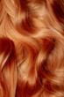 © Vera - Red hair close-up as a background. Women's long orange hair. Beautifully styled wavy shiny curls. Hair coloring bright shades. Hairdressing procedures, extension.