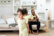 © Hip.hub - Happy African American family doing activities with daughter at home.
