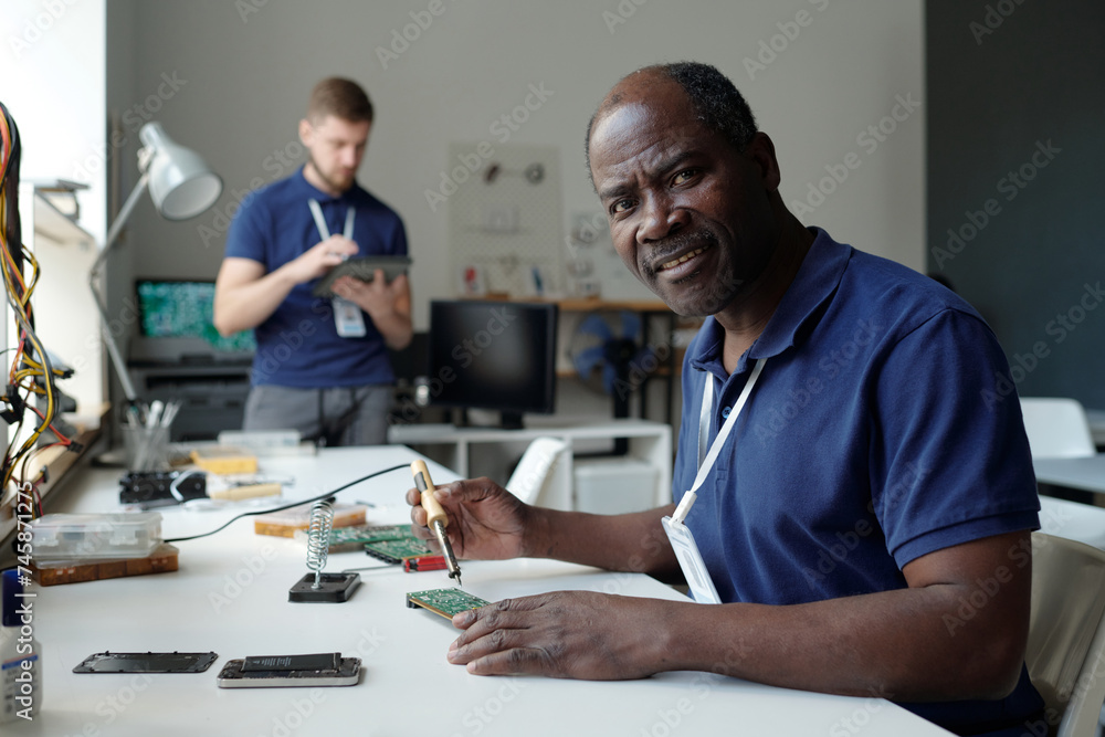 Experienced male owner of repair service laboratory looking at camera ...