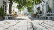 A rustic white wooden table overlooking a charming, leafy street with blurred background.