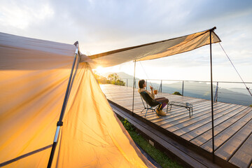 Wall Mural - Woman go camping and sit outside with the snack under sunset