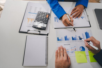 Colleagues discuss business charts and analytical prices using calculators and laptops to calculate finance, taxes, accounting, statistics, teamwork concept. Calculate personal taxes for clients