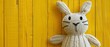 Happy Easter concept greeting card - Cute knitted easter bunny, cuddly toy, on yellow painted wooden table, wood background texture, top view, flat lay