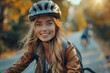 © Pinklife - Attractive young woman with a bike helmet smiling, ready for a cycling adventure in an autumn city park, with autumn foliage
