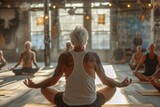 Fototapeta Natura - An older tattooed man in a yoga pose meditating in a group class, signifying mindfulness and health