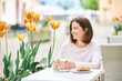 Portrait of happy mature woman having coffee with croissant in outdoor cafe