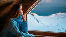In her loneliness, a young woman looks out the window at the snowy winter landscape and wishes for security