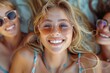 © Pinklife - Overhead shot of three smiling friends with sunglasses enjoying a beach day