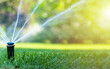 Irrigation system in home garden. Automatic lawn sprinkler watering green grass. Selective focus.