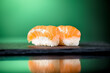 Close up of two pieces of salmon nigiri with green background