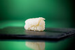 Close up of one piece of codfish nigiri with green background