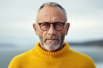 Wall Mural - Elderly man in glasses, with beard, in yellow knitted sweater on autumn nature background