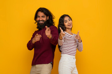 Wall Mural - Positive young indian man and woman pointing at camera