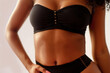 © Lazy_Bear - Cropped image of sexy young woman in black lingerie posing in studio. Slender woman with toned stomach showing her body with perfect skin without cellulite