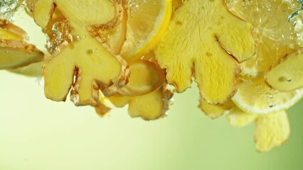 Poster - Super Slow Motion of Falling Ginger and Lemon Pieces into Water. Isolated on Colored Background. Filmed on High Speed Cinema Camera, 1000 fps.