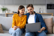 © Prostock-studio - Happy couple sharing laptop moment on the couch