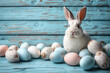 Cute adult white bunny, next to some Easter eggs on light blue aged wooden background , copy space