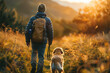 In the warm glow of the sunset, a hiker and his faithful dog explore the golden beauty of the countryside.
