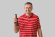 © Pixel-Shot - Mature man with bottle of beer on grey background