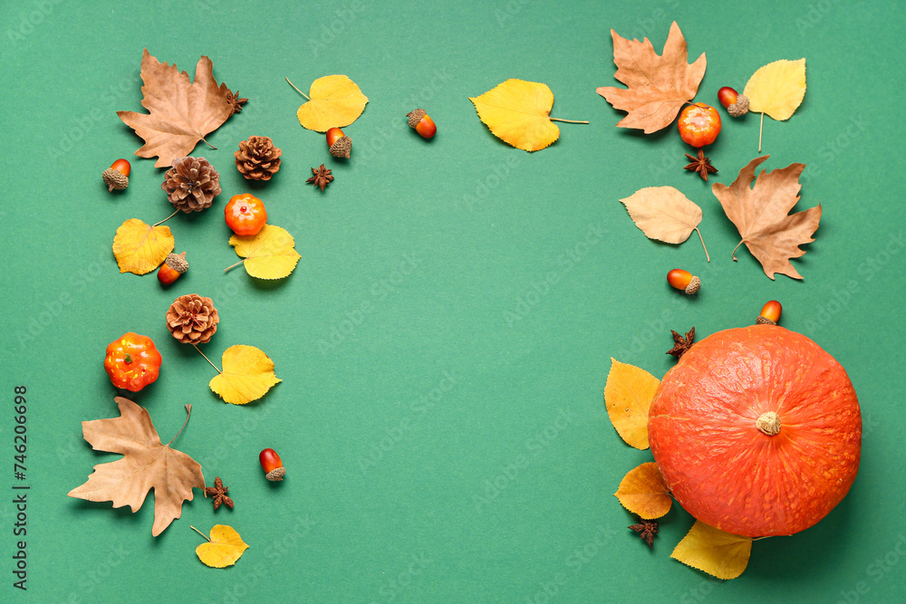 Autumn composition with ripe pumpkins, pine cones, spices and fallen leaves on green background