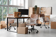 © Pixel-Shot - Interior of modern office with chairs wrapped in stretch film and cardboard boxes on moving day