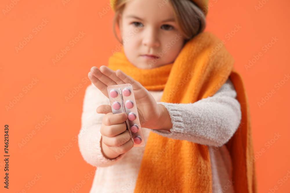 Sick little girl with pills on orange background, closeup