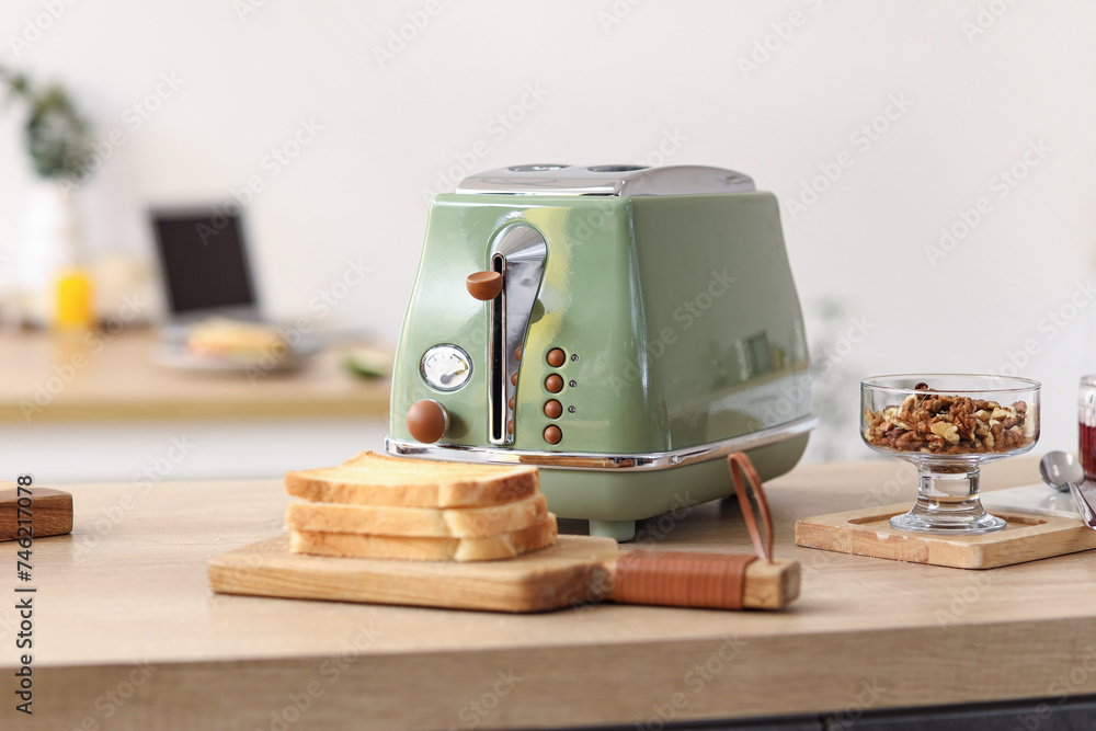 Modern toaster with crispy toasts and nuts on wooden counter in kitchen