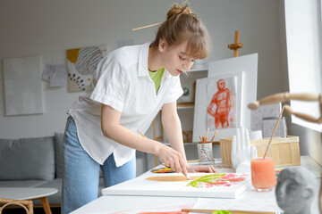 Canvas Print - Female artist painting flowers at table in workshop