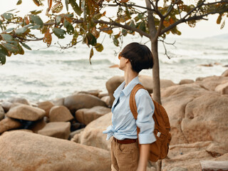 Sticker - Carefree woman walking along the tropical beach, backpack on, enjoying a happy sunset adventure on a summer vacation.