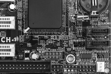 closeup of circuit board with resistors, condensers, microchips and electronic components. b/w.