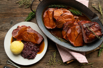 Wall Mural - Roast pork with dumpling, red cabbage and gravy on rustic background. Traditional german sunday and holiday roast