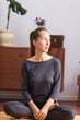 © vagon - A young adult woman sits in the lotus position in a room and meditates. Vertical composition