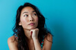 Portrait of pensive asian woman isolated on blue