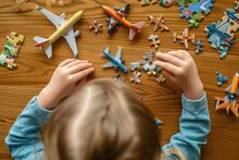 A boy is playing with toy airplanes and puzzles on the table. View from above. Close-up.