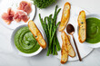 Healthy asparagus, green peas, watercress cream soup with toasted bread and prosciutto