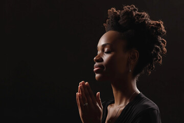 African American woman prays to god on black studio background