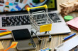 A small shopping cart on a laptop keyboard computer technology and commerce in a modern still life composition, shopping online concept