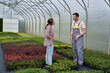 © gpointstudio - Two caucasian botanists standing in the greenhouse and discussing
