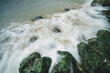 Flowing sea water from a wave splash over rocks and makes smooth misty Long exposure picture