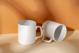 Fototapeta Mapy - White ceramic mugs on peach background with shadows