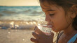 Close up: Little girl drinking water on the beach.