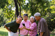 © Prot - Group of happy Senior Retirement Using Smartphone and laughing outdoors at the park after a workout and spending time together, concepts about the elderly, seniority, and wellness aging
