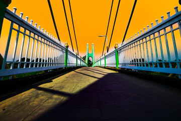 Sticker - Green suspension bridge with yellow sky across Nan River at Chum Saeng District