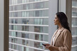 © ReeldealHD images - Businesswoman looking out of office in a skyscraper at the view holding a cell phone